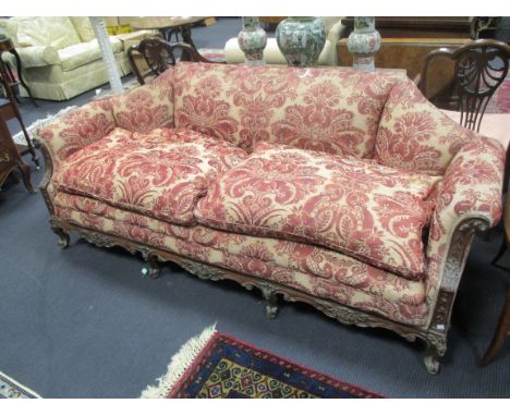 An 18th century style mahogany three seater sofa with canted back on carved legs, upholstered in a red damask, the frame carv