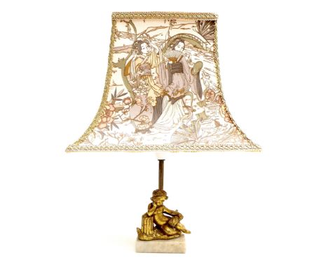 A modern figural table lamp, with reclining cherub on white stone base, gilt fluted column and lamp holder, with a fabric sha