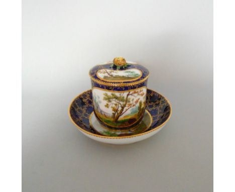 A Vincennes chocolate cup cover and saucer, painted with a river scenes of boys fishing on a blue and gilt ground, cover has 