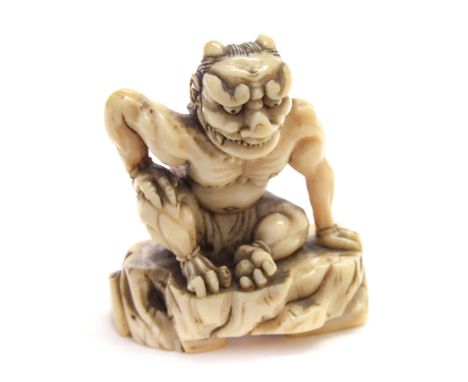 An Oriental ivory netsuke, 18th/19th Century, carved as a seated horned demon grinning with his right arm restingup on his kn