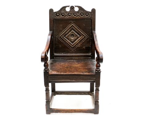 A Charles II oak joined Wainscot armchair, circa 1670, the crest rail with a broken pediment and central finial, lozenge carv