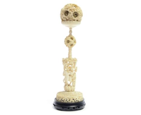 A late 19th Century Chinese ivory puzzle ball on stand, the 10cm diameter ball carved in high relief with dragons, the stand 