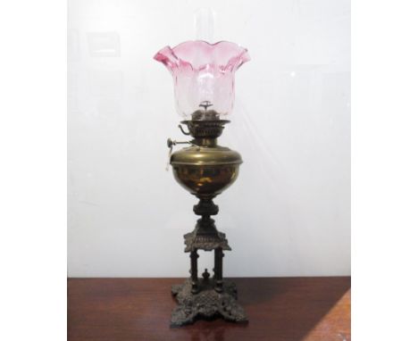 A Victorian Veritas oil lamp with cranberry shade, brass reservoir, ornate cast four pillar base stamped Rd 250115, 71cm tall
