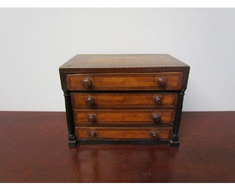 A 19th Century miniature chest of four drawers with pillar detail and quarter veneered embellishment, one handle a/f, 19.5cm 