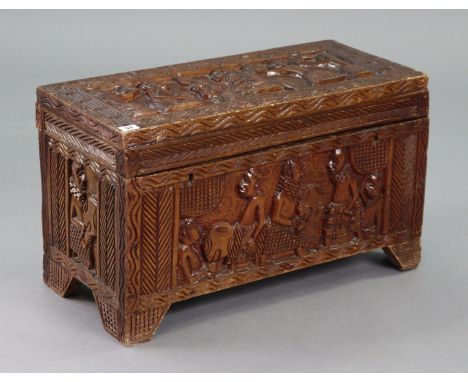 An African carved hardwood trunk with all-over figure-scene decoration, with a hinged lift-lid, & on bracket feet, 26” wide x
