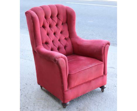 A mid-20th century button-back armchair upholstered crimson velour, &amp; on bun feet with Shepherd castors.