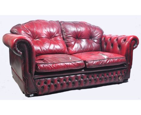 A vintage 20th Century antique style Chesterfield two seater sofa settee in a deep oxblood scarlet red leather having button 