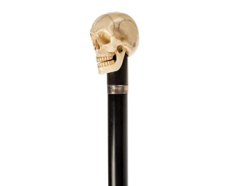 *Walking Cane. A 19th century walking stick,  with finely carved ivory skull on an ebony shaft with silver collar and horn fe