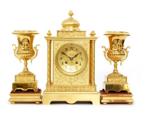 A late 19th Century eight day strike gilt mantle clock garniture, the dial with Arabic numerals flanked by four column suppor