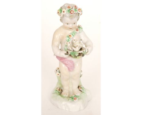 A late 18th to early 19th Century Derby figure of a standing cherub wearing a garland of flowers in his hair and as a sash ho
