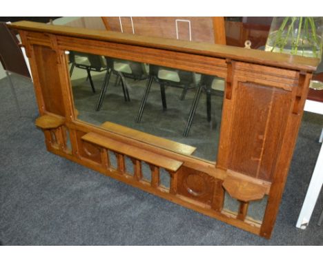 An early 20th Century Arts and Crafts oak overmantle mirror, the cornice top above a pair of corbel brackets flanking a centr
