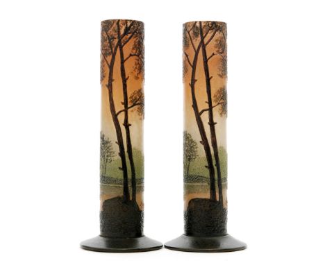 A pair of early 20th Century Legras glass posy vases of footed sleeve form, enamel decorated with trees amongst a natural lan