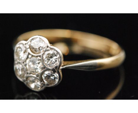 An 18ct diamond daisy cluster ring, seven brilliant cut diamonds set to a petalled flower head setting, plain tapering band, 