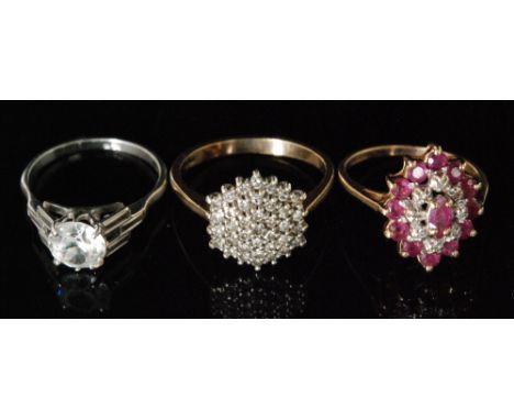 A 9ct ruby and diamond cluster ring, oval pierced head with mixed cut claw set rubies and diamonds to a plain tapering band, 