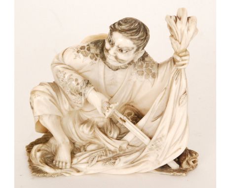 A late 19th Century Japanese carved ivory warrior piercing a cloak with a sword, red tablet missing to base, height 9cm