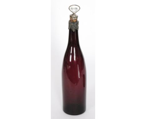 A 19th Century glass spirit decanter of bottle form in amethyst with white metal mounts with fruiting vine decoration rising 