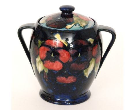 A Moorcroft twin handled biscuit barrel of tapering form decorated in the Pansy pattern with a band of flowers and foliage ag
