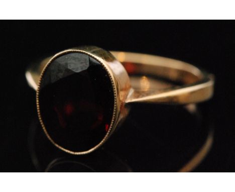 A 9ct hallmarked single stone garnet ring, oval collar set stone to knife edged shoulders, ring size M, Birmingham 1970, Bern