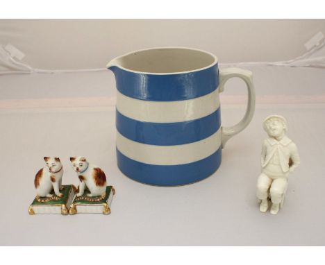 A white Worcester porcelain figure of a boy sat on a chair and a blue and white Cornish ware jug by 'T.G. Green' together wit