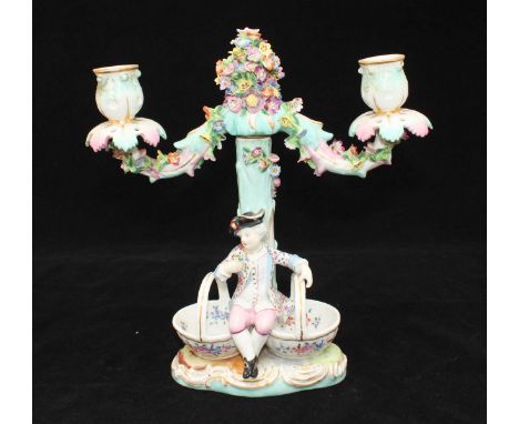 A 19th century Meissen porcelain two-light candelabra of rustic form modelled as a flower-encrusted tree with a figure sat at
