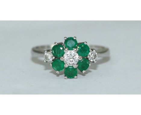 An 18ct white gold, diamond and emerald cluster ring, flower design, three diamonds estimated 0.30pts, six emeralds estimated