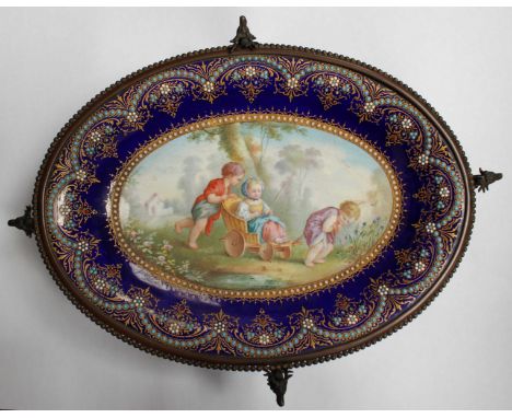 A 19th Century oval enamel dish, decorated with a scene of children playing in a cart, surrounded by gilt and jeweled decorat
