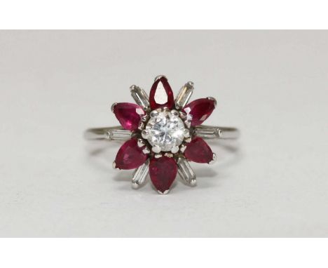 An 18 carat white gold cluster ring claw set with a central round brilliant cut diamond surrounded by six pear shaped rubies 