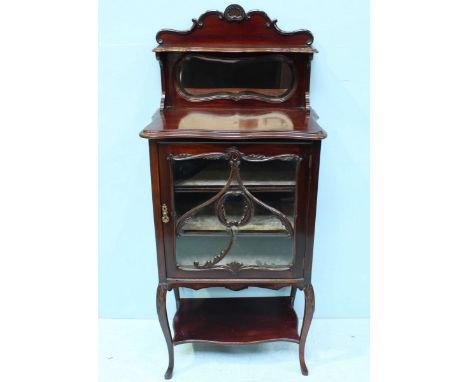 An Edwardian mahogany display cabinet, with shelf and mirrored back, above a single glazed door enclosing two shelves, over a