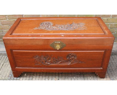 A Chinese rosewood trunk, the hinged top carved with scenes of figures and pagodas and opening to reveal a camphor wood lined