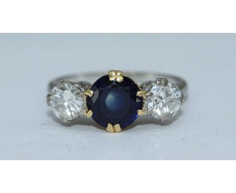 An 18ct gold sapphire and diamond ring, centrally claw-set a round faceted sapphire measuring 7.76mm, flanked by two RBC diam