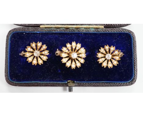 A cased graduated set of three Edwardian yellow metal, seed pearl and diamond set flower head brooches, largest diameter 18mm