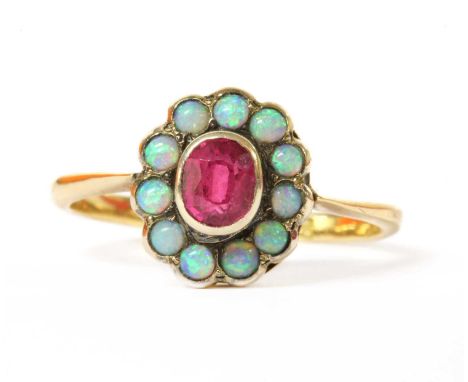 A gold ruby and opal cluster ring, an oval mixed cut ruby, possibly synthetic, rub set to the centre, to surround of round ca