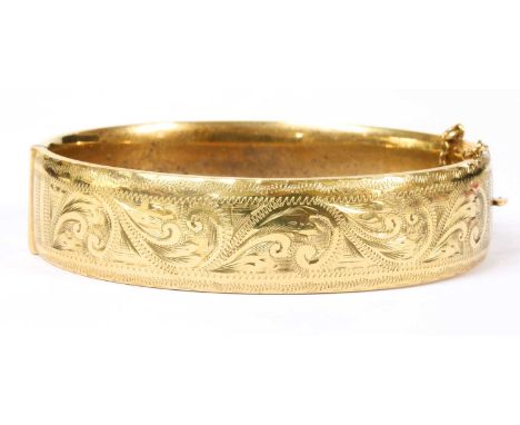 A 9ct gold oval hinged bangle, with hand engraved decoration to the upper half, and plain polished lower half, with concealed