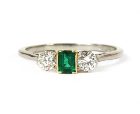 A platinum and gold, emerald and diamond three stone ring, a rectangular step cut emerald, semi rub set in yellow gold, with 