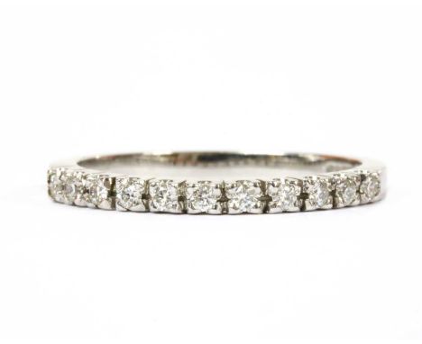 An 18ct white gold diamond half eternity ring, with a row of brilliant cut diamonds, claw set, to flat section shank, London 