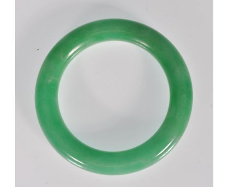 A Chinese green jade bangle of typical round form. Interior diameter 5.4cm. Weighs 73g.