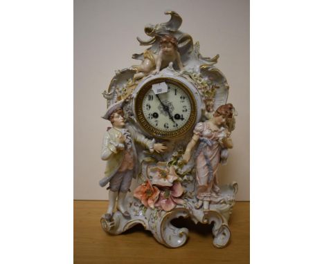 A Sitzendorf or Thuringia porcelain figural mantel clock, the dial with Arabic hours, flanked and surmounted by figures decor