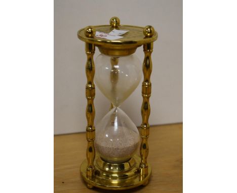 A brass and glass egg timer, of traditional hour glass form with brass surmount and base with three uprights, chinoiserie sce