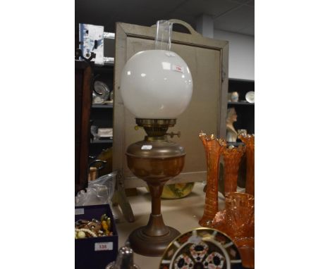 A vintage brass oil lamp with shade and chimney.
