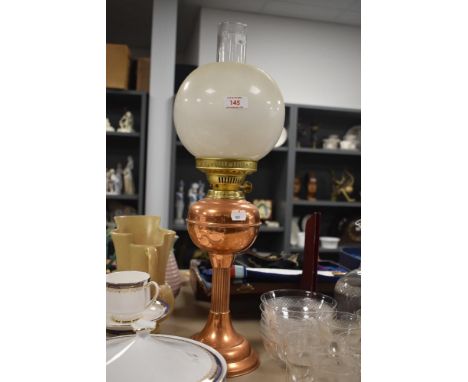 A vintage copper and brass oil lamp with a column style base, having chimney and shade.