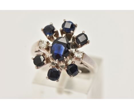 A SAPPHIRE AND DIAMOND DRESS RING, designed as a central oval sapphire flanked by two single cut diamonds within a circular s