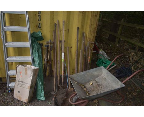 A SELECTION AN WOODEN GARDEN HAND TOOLS, including rakes, forks, shovels, etc, a galvanised wheel barrow and an aluminium ste