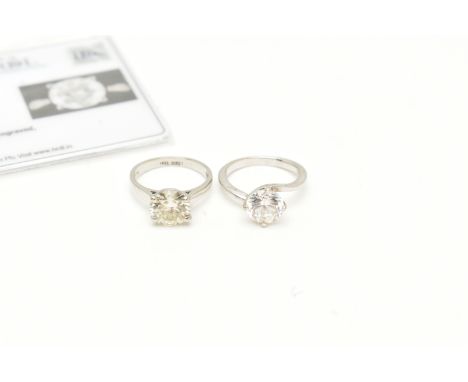 A MOISSANITE WHITE METAL SINGLE STONE RING AND A PASTE WHITE METAL RING, the circular cut moissanite, within a four claw sett
