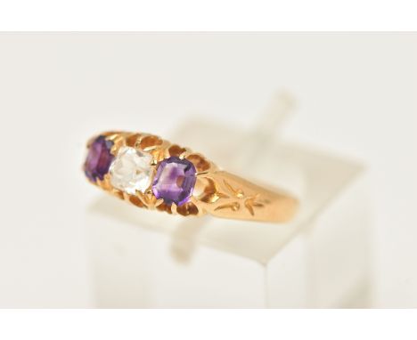 AN 18CT GOLD AMETHYST AND PASTE RING, set with a cushion cut colourless paste, flanked with two rectangular cut amethysts wit