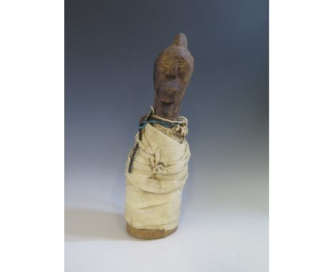 A Liberian Mano or Geh Carved Wooden Figure wrapped in cloth with beads, shells and coins and with magical substances in stom