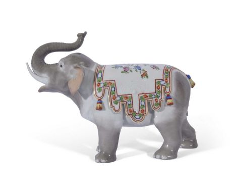 Continental porcelain model of an elephant with trunk raised, the back with a floral design and with tassels in Meissen style