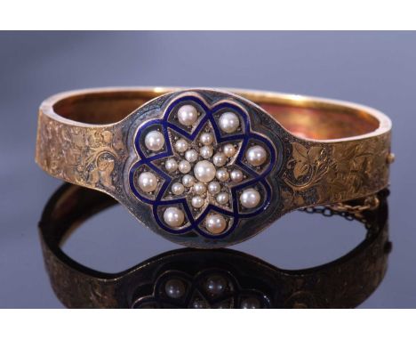 Early 20th century enamel and seed pearl hinged bracelet, the top section with chased and engraved detail, the centre applied