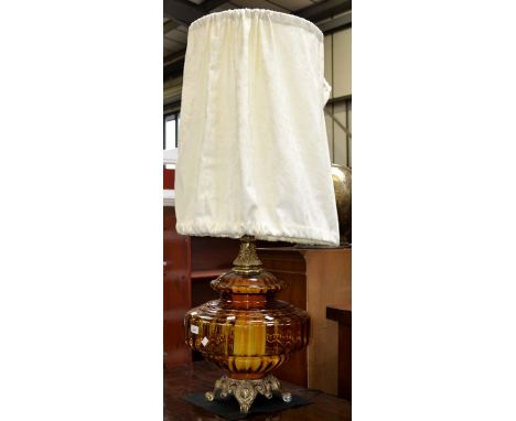 A 1960's amber glass table lamp, laureate gilt brass neck, lion paw feet, shaped apron, 112.5cm high overall