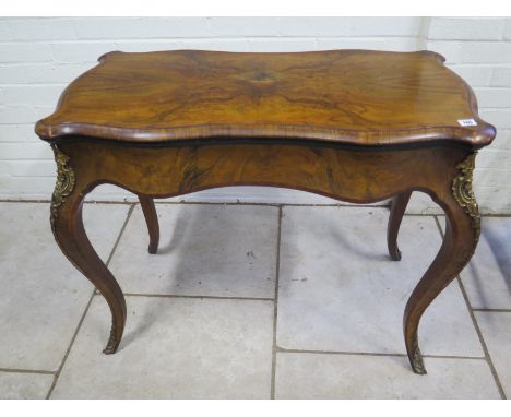 A 19th Century walnut fold over card table with a shaped top on cabriole legs, with ormulu mounts, 75cm H x 94cm 