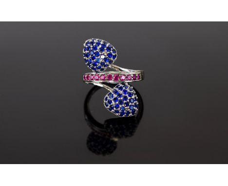 Sapphire and Ruby Cluster Crossover Ring, small blue sapphires set as two domed trillions, in silver, forming a crossover sty